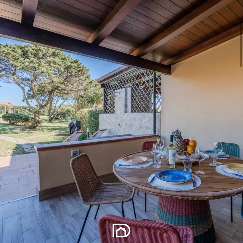 Veranda con tavolo da pranzo e giardino di un immobile in Sardegna